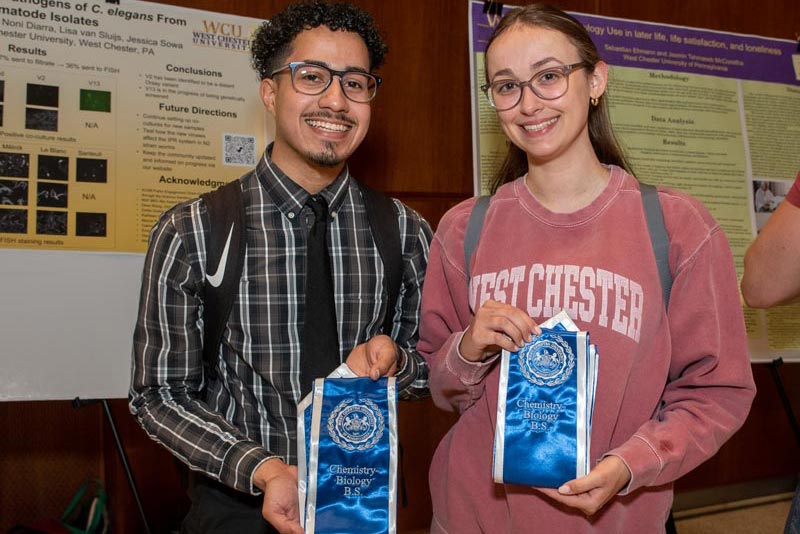 Image from a past years Research and Creative Activity Day - 2 people hold up Chemistry Biolog B.S. sashes