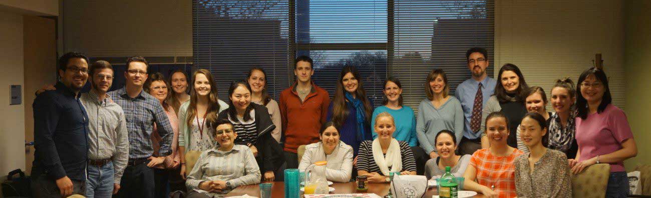 Group photo - 17 people standing and 6 sitting at a table.