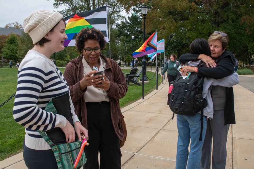 Students standing outside with pride flags in the background.