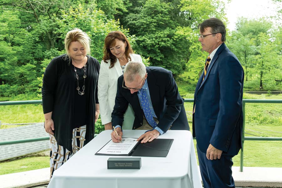 West Chester University and East Whiteland Township held a formal signing ceremony to celebrate their historic partnership in preserving a 52-acre farm that was gifted by an anonymous donor. Pictured (L to R) are University President Dr. Laurie Bernotsky, Executive Director of the West Chester University Foundation Deb Cornelius, East Whiteland Township Manager Steve Brown (signing), and Chairman of the East Whiteland Township Board of Supervisors Scott Lambert. [Photo taken by Melissa Kelly]