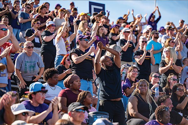 The crowd of fans on the bleachers at the WCU homecoming game look as though they are clapping and celebrating