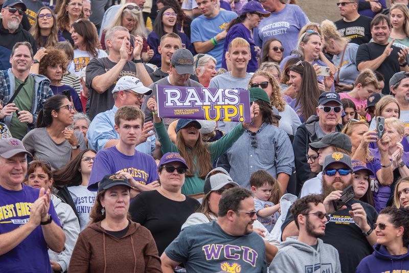 homecoming crowd; someone holds up a sign saying Rams Up!