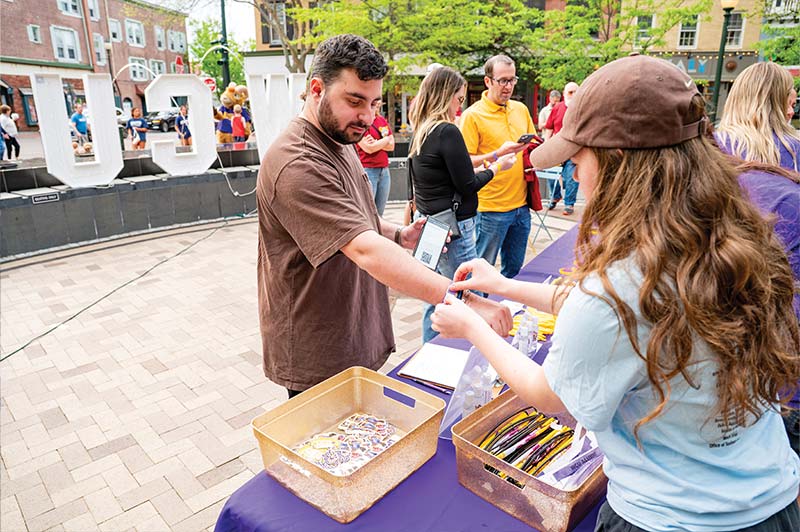 A person gets fitted with their event wristband at the entrance table