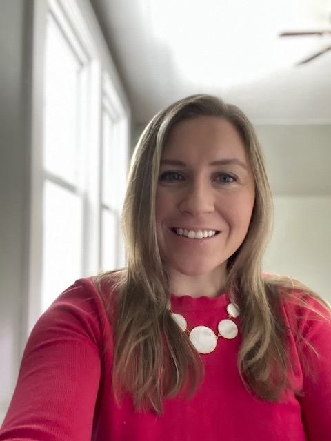 Alumna Katie Graham in a bright red sweater smiling.