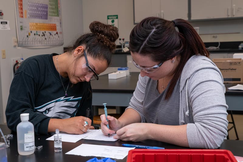 Forensic Microscopy Students wearing goggles in the lab and taking notes