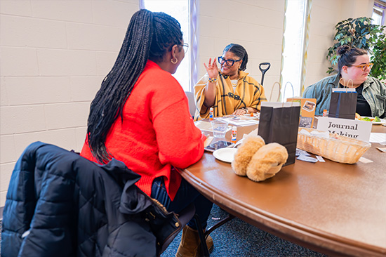 Candid photo from the Frederick Douglass day event. 2 patrons talking at a table.